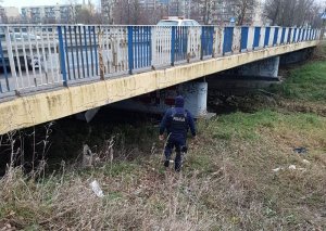 policjant sprawdza czy pod mostem nie znajdują sie bezdomni