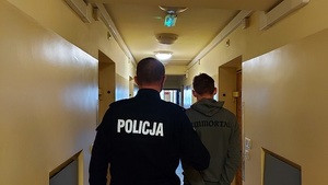 korytarz aresztu, policjant prowadzi zatrzymanego