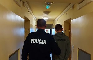 korytarz aresztu, policjant prowadzi zatrzymanego