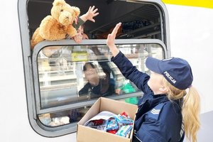 policjantka przybija piątkę przez okno w wagonie z chłopcem, w oknie widać pluszowego misia