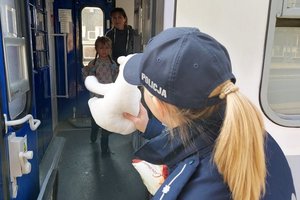 policjantka podaje dziecku misia, dziewczynka stoi w drzwiach pociągu