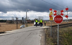 znak stop przed przejazdem kolejowym za torami policjant , funkcjonariusze SOK rozmawiają z kierowca samochodu