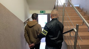 policjant sprowadza zatrzymanego po schodach