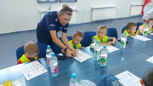 policjantka robi odciski palców dzieciom, dzieci siedzą przy stole