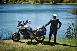 policjant oparty o motocykl stoi nad zbiornikiem wodnym