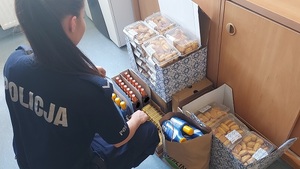 policjantka kuca przy zabezpieczonym towarze słodycze, kosmetyki leżą na podłodze