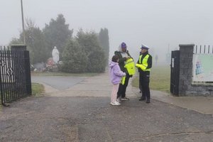 policjantka w bramie cmentarza rozdaje kamizelki