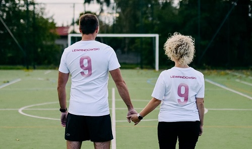 boisko piłkarskie tyłem stoją mężczyzna i kobieta w koszulkach białych z napisem Lewandowski i numerem 9