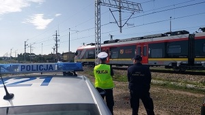 policjant i funkcjonariusz straży ochrony kolei przed przejazdem kolejowym.