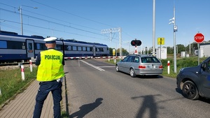 policjant stojący przed przejazdem kolejowym.