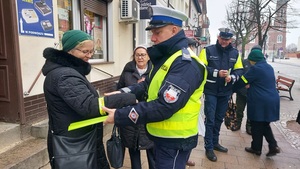 policjanci rozdają elementy odblaskowe pieszym.