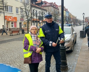 policjanci rozdają elementy odblaskowe pieszym.