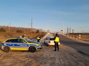 Przejazd kolejowy, kontrola pojazdu przez policjanta ruchu drogowego w obecności funkcjonariusza Straży Ochrony Kolei.
