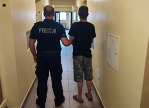 policjant prowadzacy zatrzymanego mężczyznę.