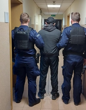 policjanci prowadzą zatrzymanego mężczyznę.