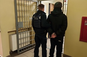 policjanci prowadzą zatrzymanego mężczyznę.