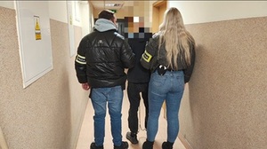 policjanci prowadza zatrzymanego mężczyznę.