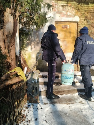 dzielnicowi wnoszą butlę gazową do pustostanu.