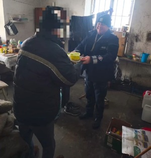 policjant daje mężczyźnie ciepły posiłek.
