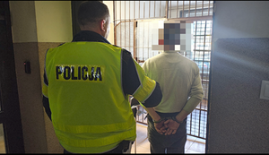 policjant trzyma zatrzymanego mężczyznę.