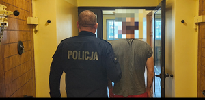 policjant prowadzi zatrzymanego mężczyznę.