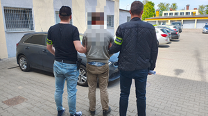 policjanci prowadzą zatrzymanego mężczyznę do radiowozu.