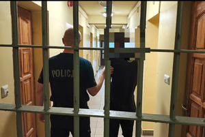 policjant prowadzi zatrzymanego mężczyznę.