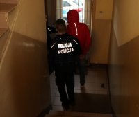 policjanci prowadzą zatrzymanego.