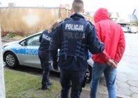 policjanci prowadzą zatrzymanego.