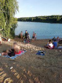 policjanci podczas działań prewencyjnych nad wodą, w tle woda oraz ludzie na plaży.