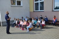 policyjni profilaktycy podczas spotkania na placu szkolnym rozmawiają z dziećmi o bezpieczeństwie.