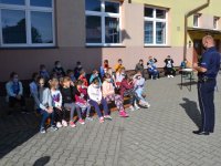 policyjni profilaktycy podczas spotkania na placu szkolnym rozmawiają z dziećmi o bezpieczeństwie.