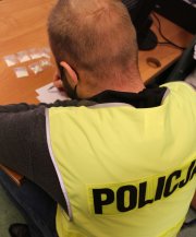 funkcjonariusz w kamizelce z napisem POLICJA z zabezpieczonymi  7 dilerkami amfetaminy.