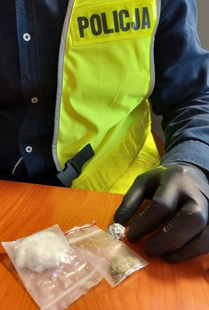 policjant w kamizelce z napisem POLICJA zabezpiecza narkotyki