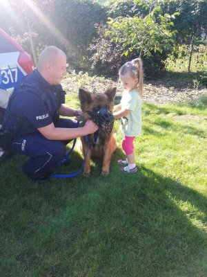 na zdjęciu policjant z psem służbowym podczas spotkania z dziećmi.