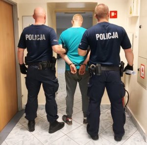 umundurowani policjanci prowadzą zatrzymanego.