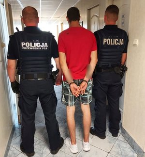 umundurowani policjanci prowadzą zatrzymanego.