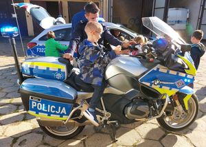 wizyta przedszkolaków w komendzie, dziecko siedzi na motocyklu policyjnym.