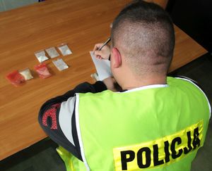 policjant w kamizelce z napisem POLICJA z zabezpieczonymi narkotykami.