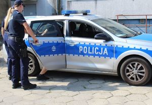 policjanci  z zatrzymanym wsiadają do radiowozu.