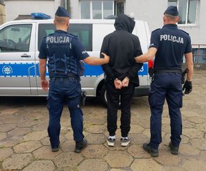 umundurowani policjanci prowadzą zatrzymanego.