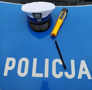 policyjna czapka i AlcoBlow na masce radiowozu w tle napis POLICJA.