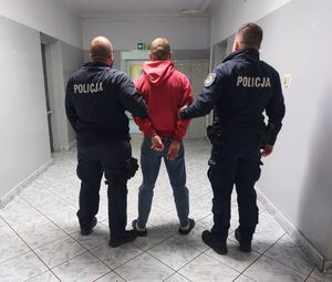 policjanci prowadzą zatrzymanego.