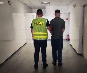 policjant prowadzi zatrzymanego.