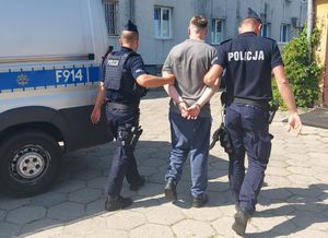umundurowani policjanci prowadzą zatrzymanego.
