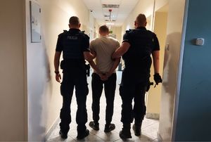 umundurowani policjanci prowadzą zatrzymanego.