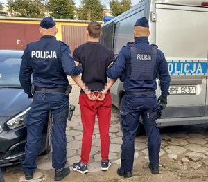 policjanci prowadzą zatrzymanego.