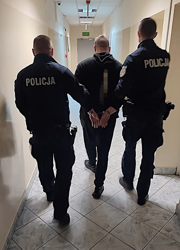 policjanci prowadzą zatrzymanego.