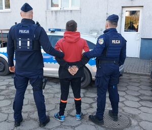 policjanci prowadzą zatrzymanego.