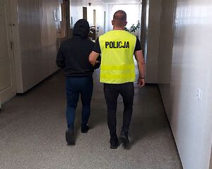 policjant prowadzi zatrzymanego.